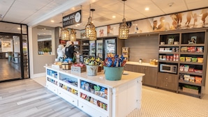 A snack bar with a variety of snacks, a coffee machine, and hanging pendant lights. - Holiday Inn Manahawkin/Long Beach Island by IHG (Manahawkin)