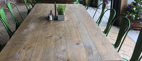 Une table en bois avec des chaises, une petite plante et un panneau indiquant la sortie.