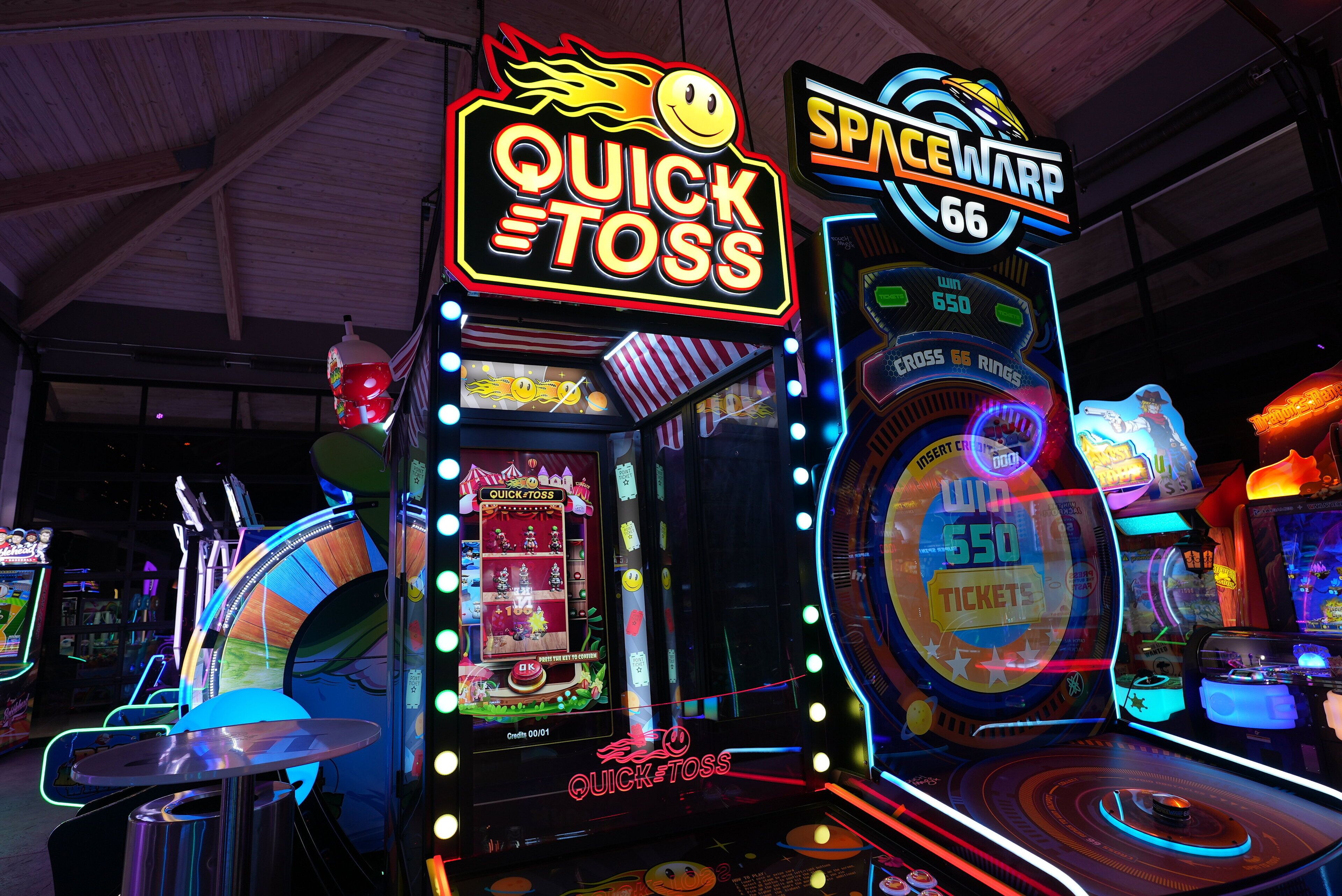Arcade machines with neon signs, including "Quick Toss" and "Spacewarp 66".