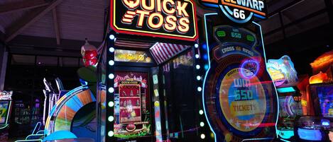 Arcade machines with neon signs, including "Quick Toss" and "Spacewarp 66".