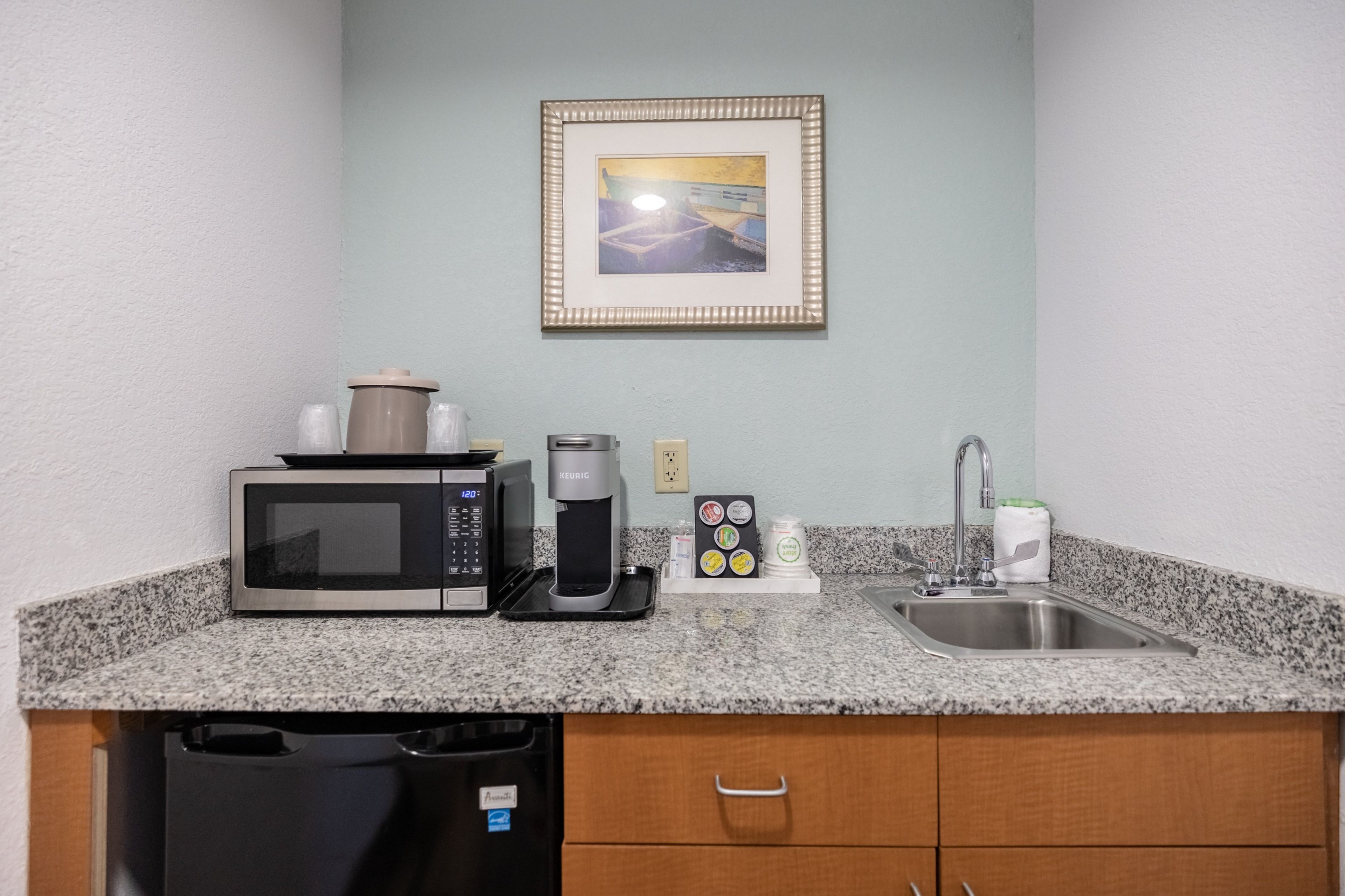 A kitchenette with a microwave, coffee maker, and a sink.