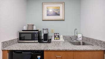 A kitchenette with a microwave, coffee maker, and a sink.