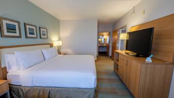 Habitación de hotel con una cama grande, un televisor sobre una cómoda de madera, un escritorio con una lámpara y cuadros en la pared.