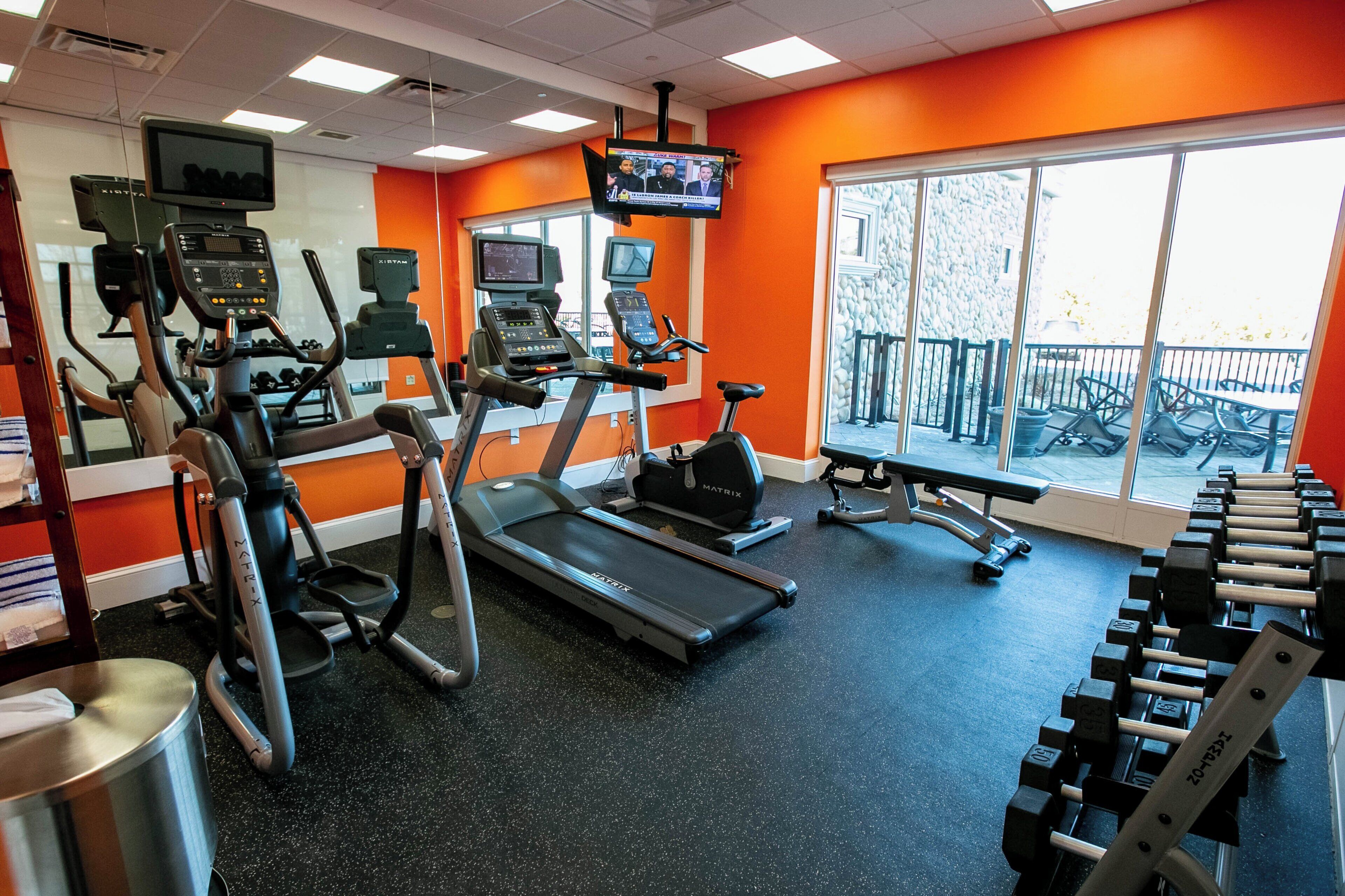 A gym with treadmills, elliptical machines, and free weights.