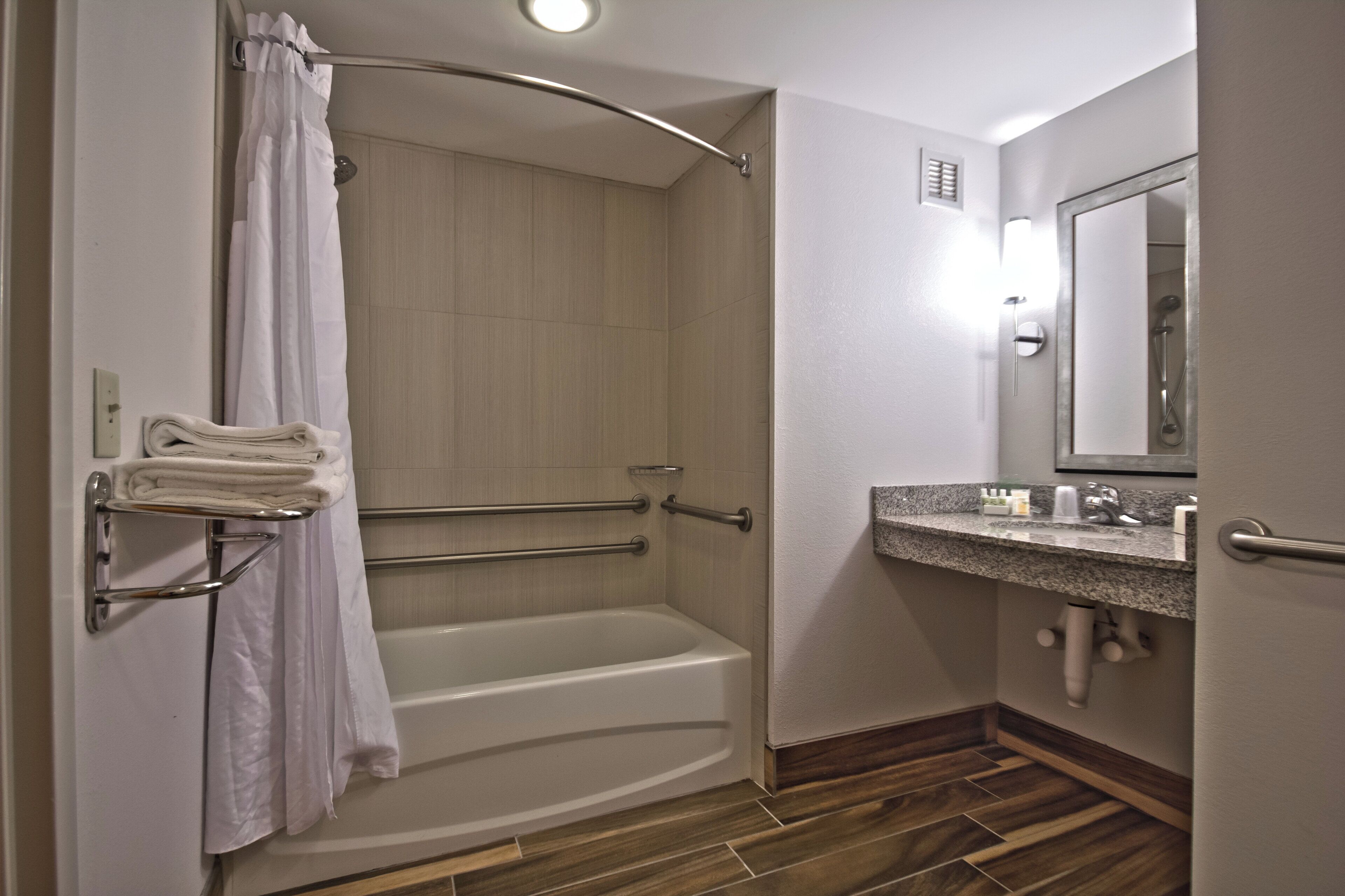A bathroom with a shower, a bathtub, a towel rack, a sink, and a mirror.