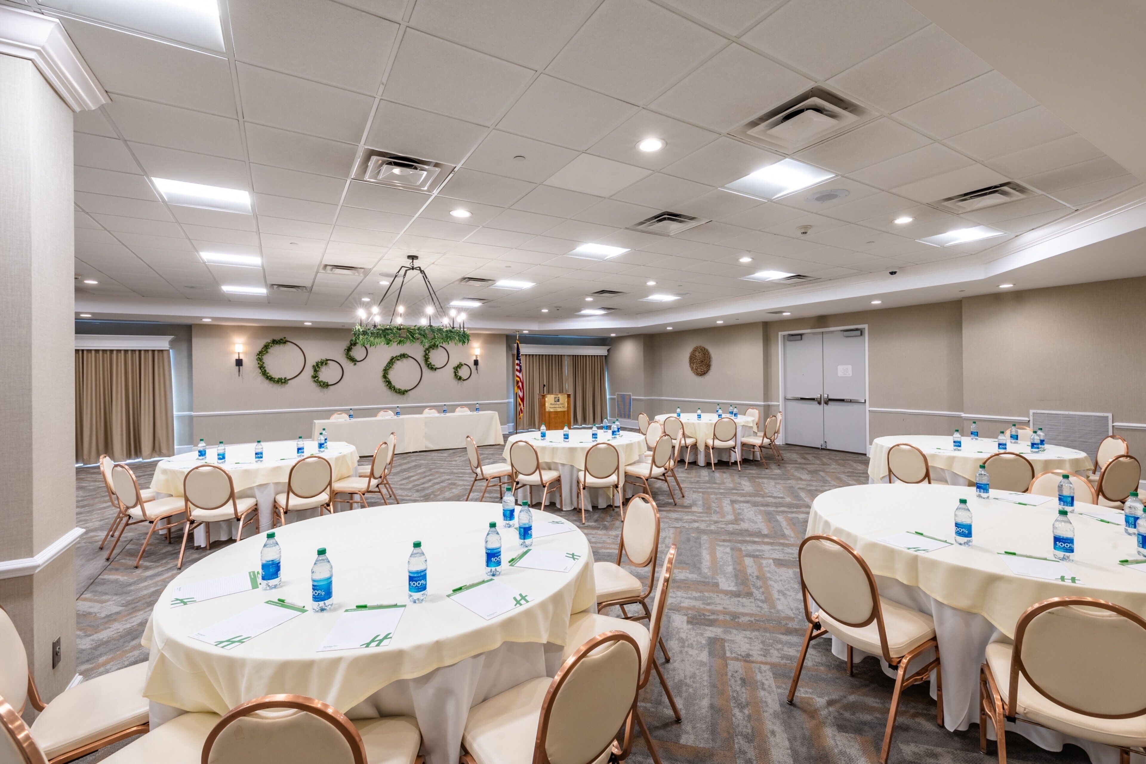 A conference room with round tables, chairs, and water bottles.