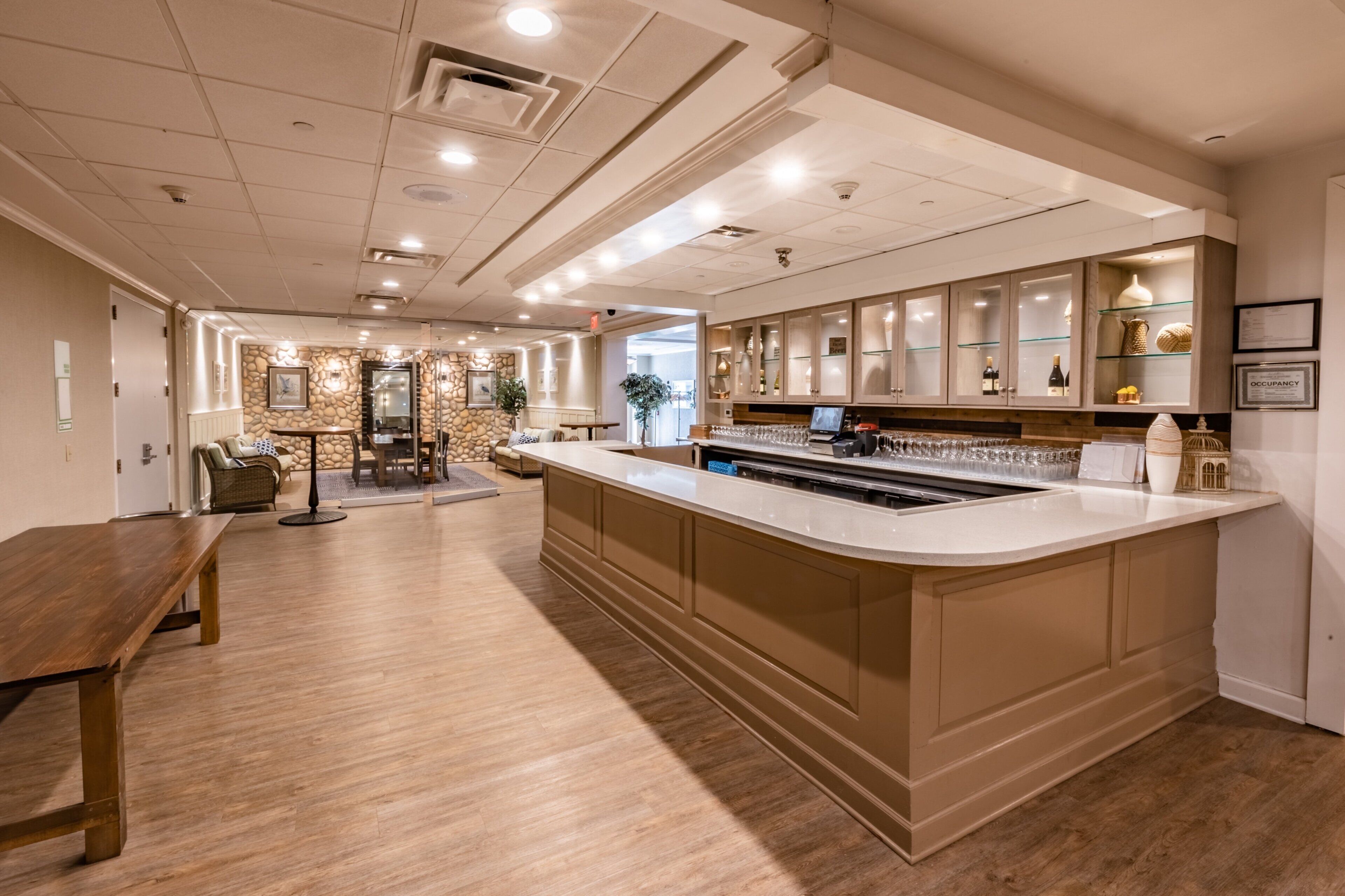 A spacious hotel lobby with a central bar area, seating arrangements, and a stone accent wall.