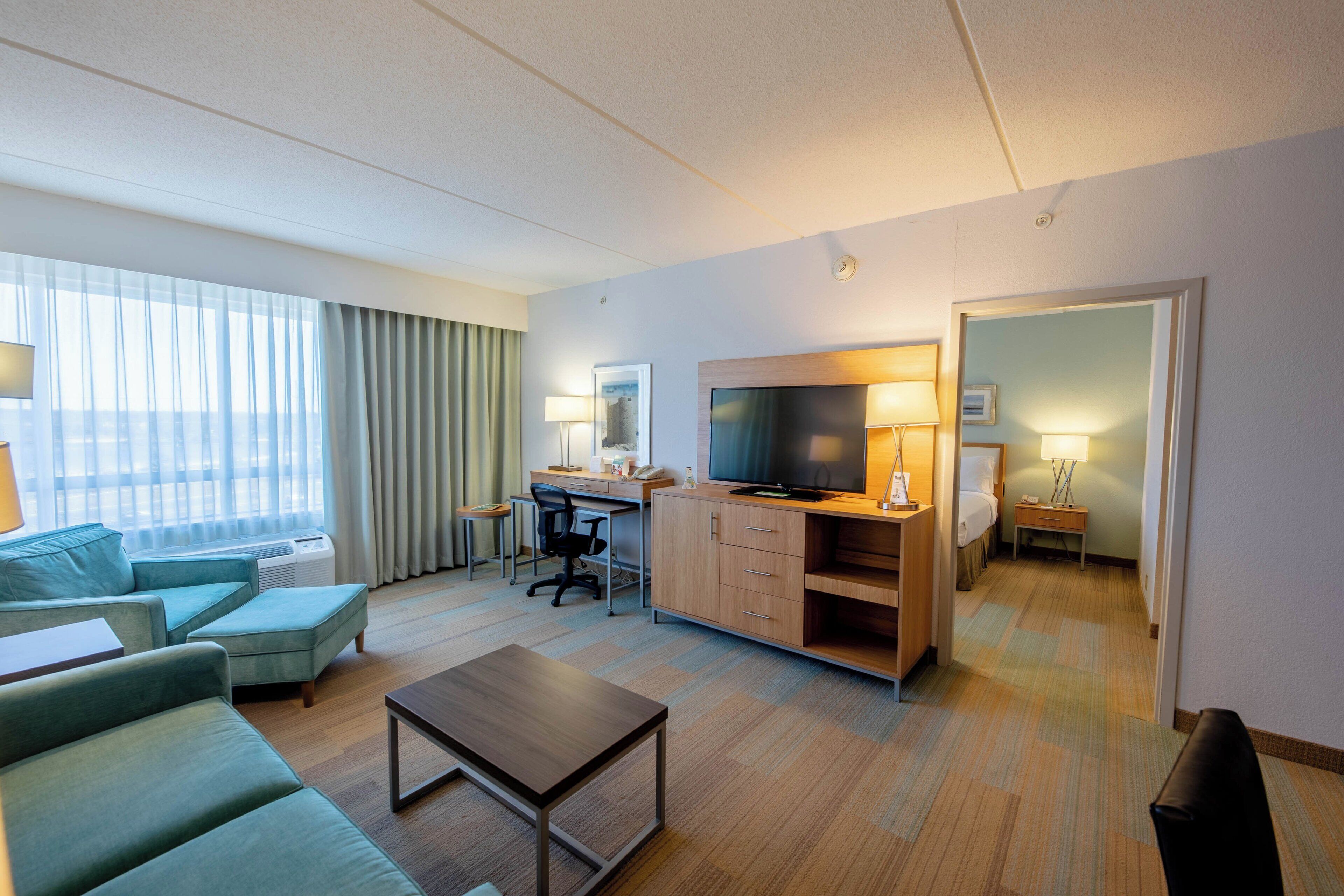 Ein Hotelzimmer mit einer Couch, einem Schreibtisch, einem Fernseher und einem Bett.