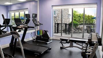 Un gimnasio con cintas de correr, elípticas y una zona de pesas.