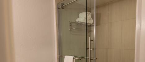 Un baño moderno con ducha cubierta por vidrio, inodoro blanco y piso de madera.
