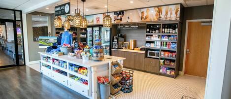L’intérieur d’un café, avec un comptoir, des étagères remplies de collations et des lampes suspendues.
