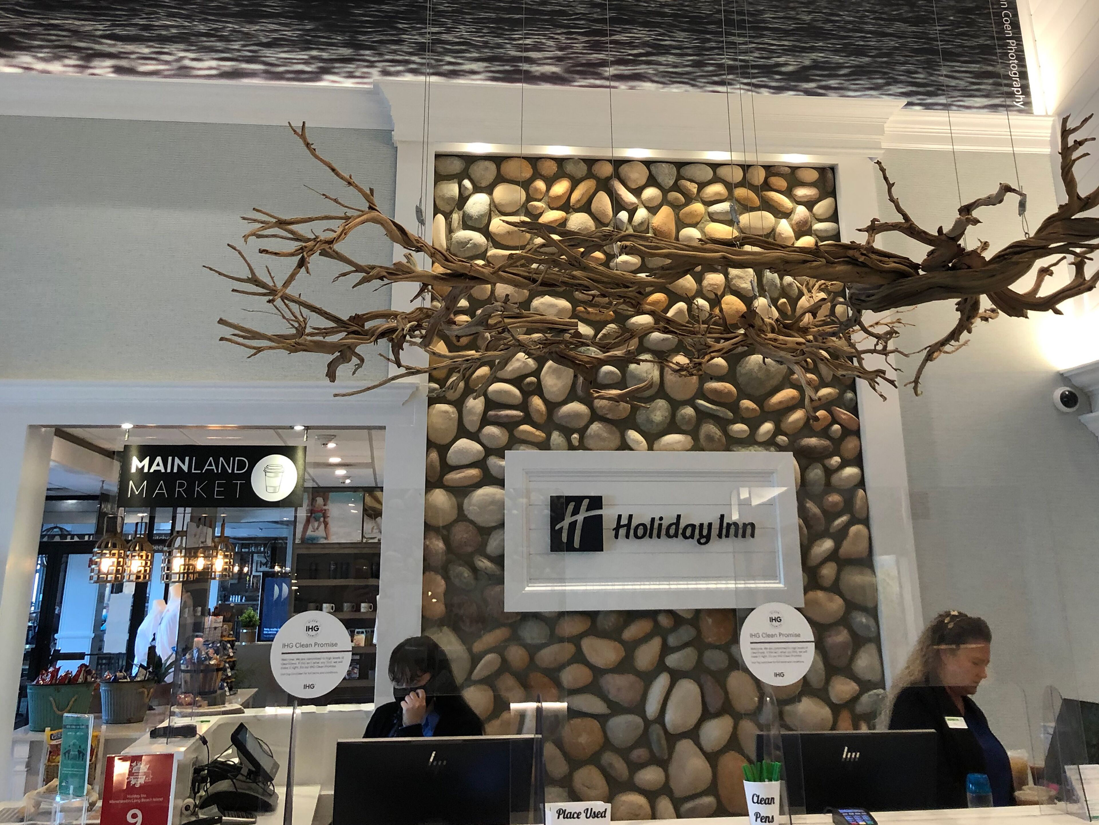 A Holiday Inn reception area with a stone wall backdrop and a branch decoration.