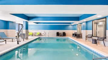 Una piscina techada, sillones reclinables de piscina