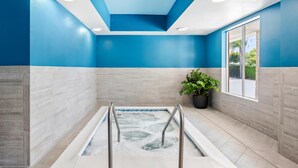 A modern bathroom with blue walls, a bathtub, a potted plant, and a window. - Hampton Inn & Suites Lathrop (Lathrop)