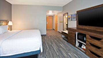 A hotel room with a bed, a flat-screen TV, a microwave, and a coffee maker.