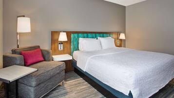 A hotel room with a bed, a sofa, a small table, and two bedside lamps.