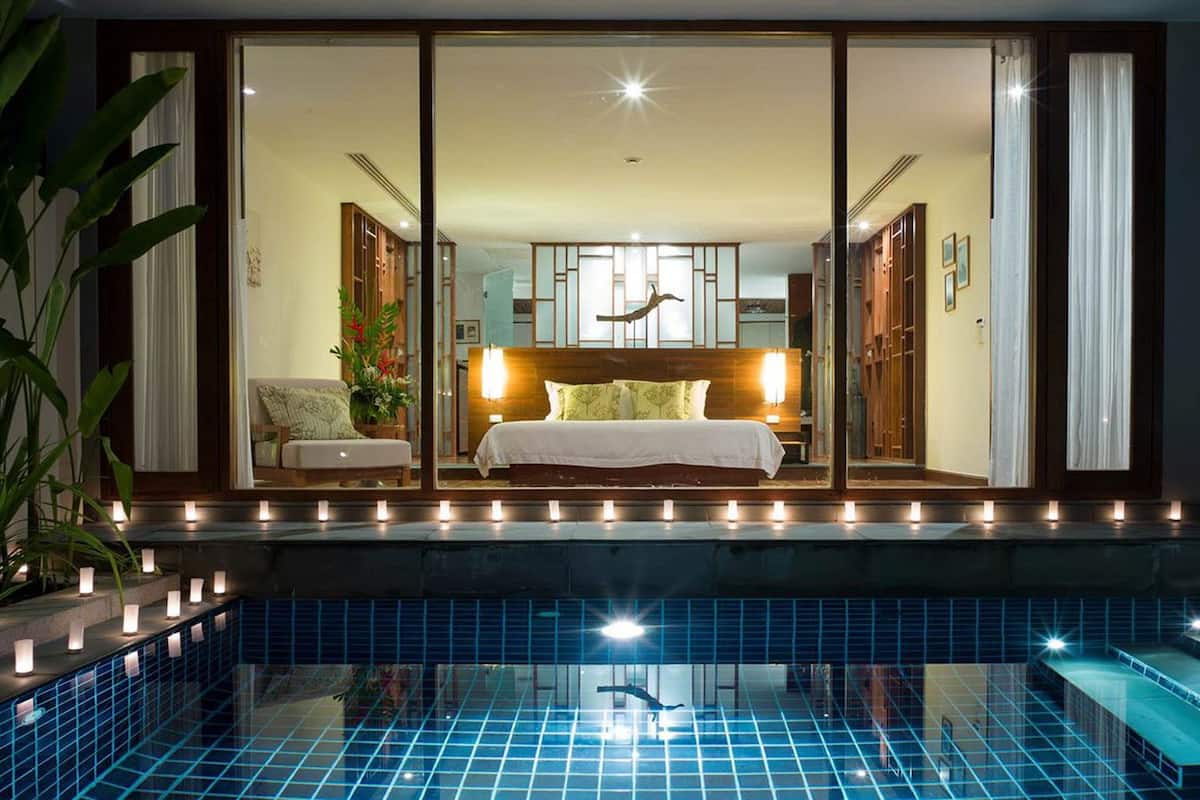 Habitación de hotel con una cama grande, vista a la piscina y puerta corredera de vidrio que da a un balcón.