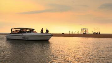 A boat named 'Lady SAROJIN' on calm water with a beach and structures in the background.