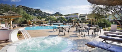 Un área de piscina con jacuzzi, sillas de descanso y mobiliario exterior.