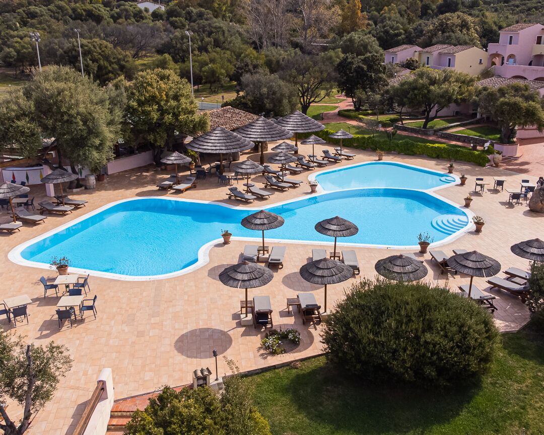 A resort with two swimming pools, sun loungers, and umbrellas.