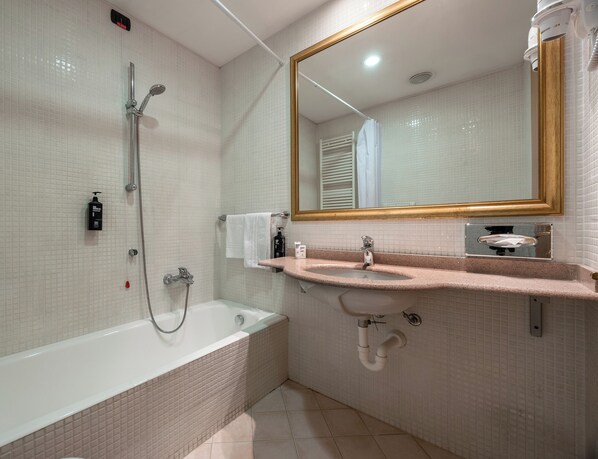 Un baño con bañera, lavabo, espejo y ducha.