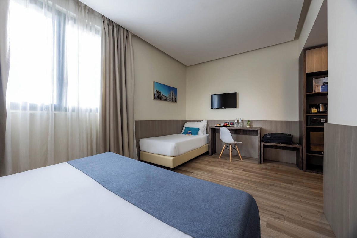 Une chambre d’hôtel équipée d’un lit, d’un bureau, d’une chaise, d’une télévision et d’une bibliothèque.