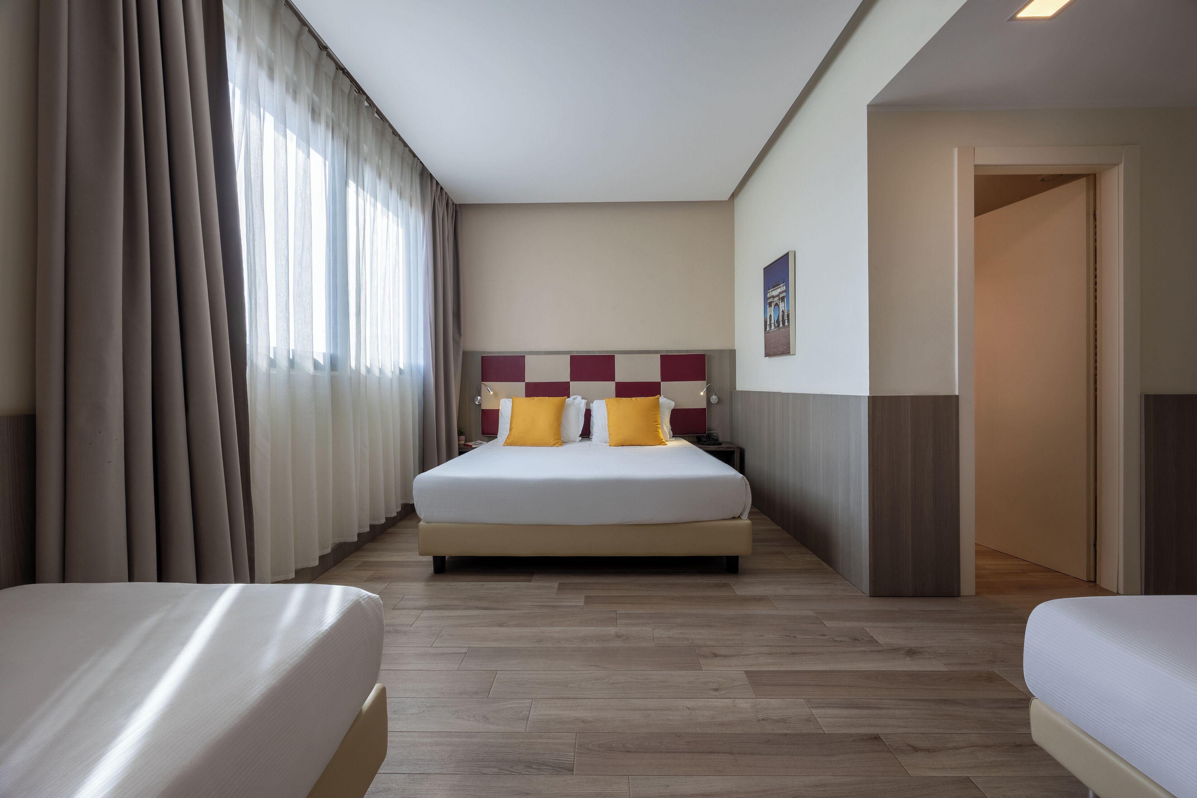 Habitación de hotel con una cama grande, dos mesitas de noche y vista al pasillo.