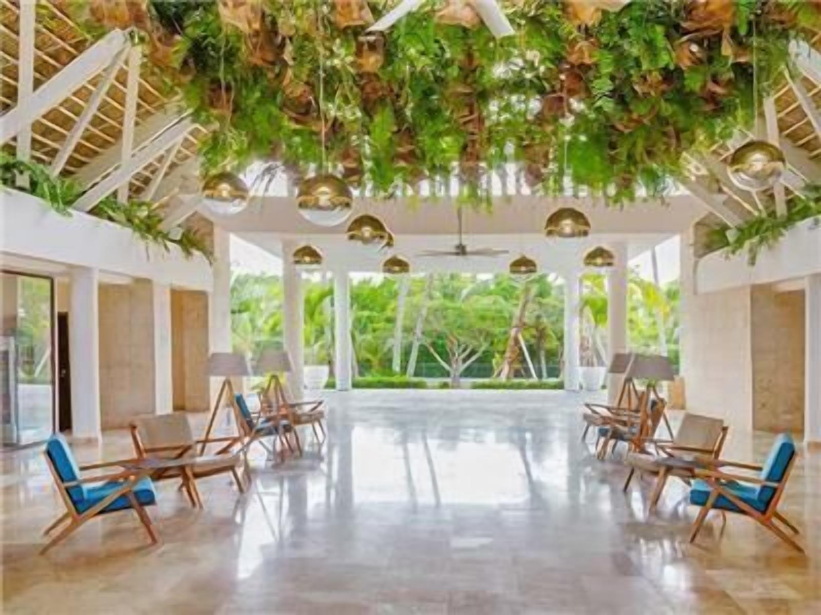 A spacious room with a high ceiling, large windows, and a view of greenery outside.