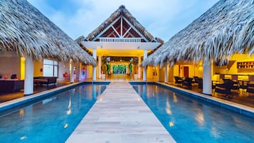 Alberca al aire libre, sombrillas en la alberca y camastros