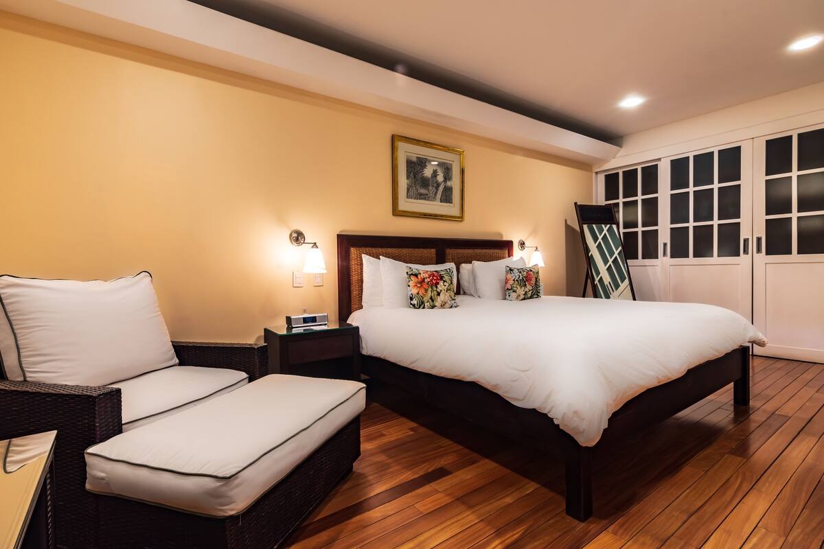 Un dormitorio con una cama grande, una mesita de noche, una silla y un armario.