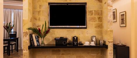 A stone fireplace with a flat-screen TV above it, a coffee maker, and a small shelf with books and decorative items.