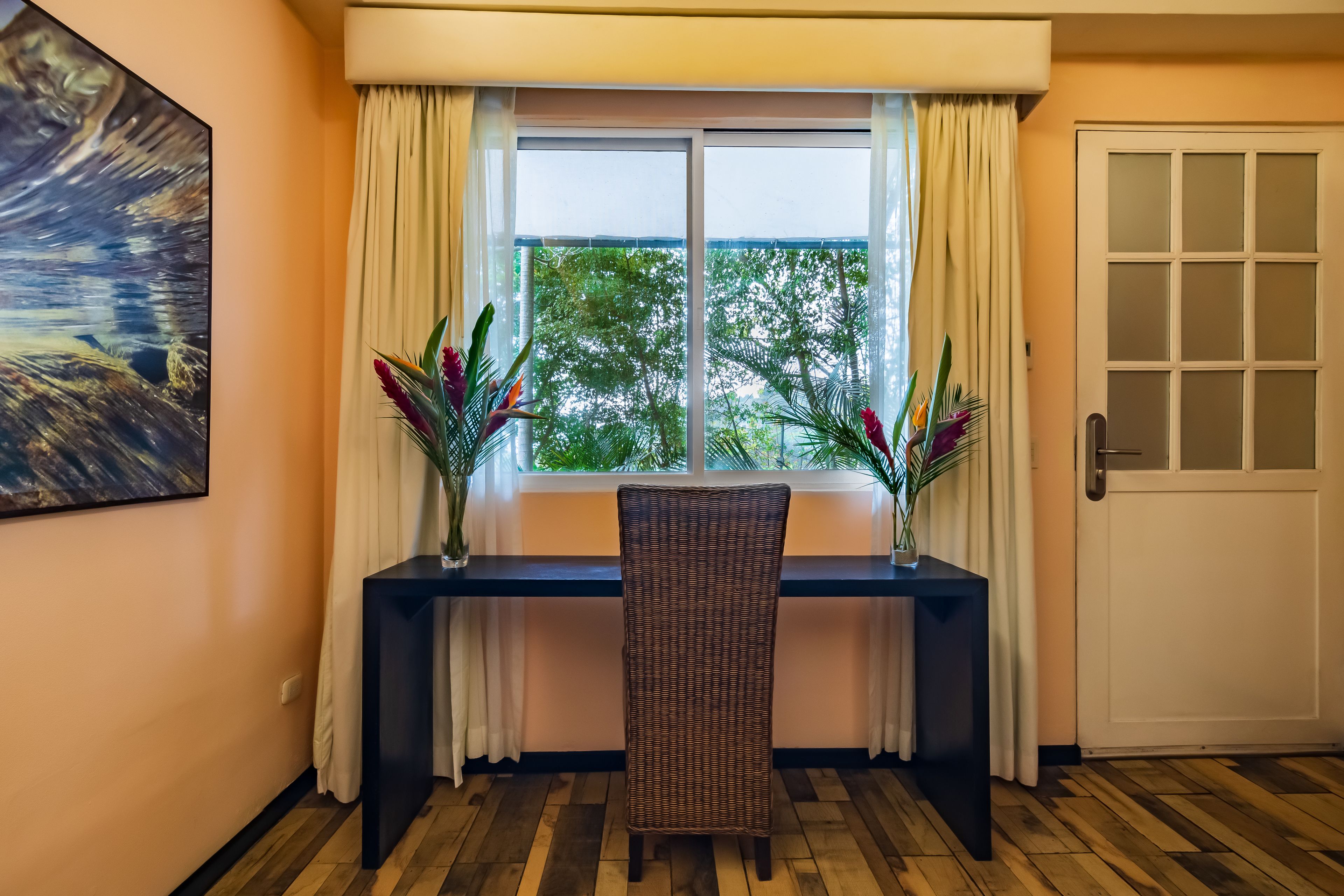 A room with a window, a chair, a desk, and a door.
