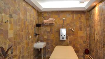 A bathroom with stone walls, a sink, a towel rack, and a shower.