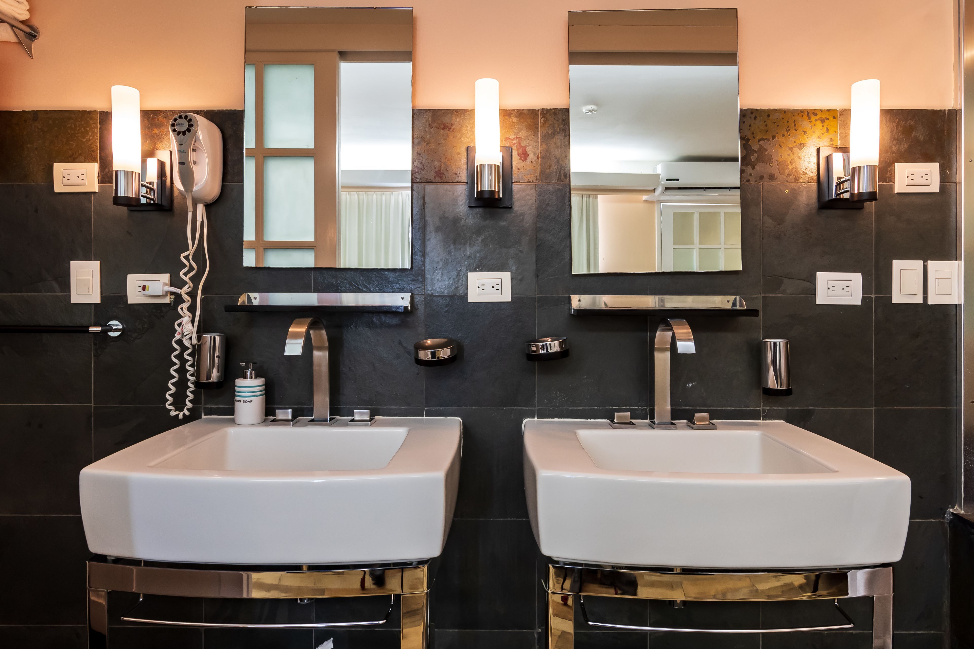Une salle de bain moderne avec deux lavabos, un sèche-cheveux et un miroir.