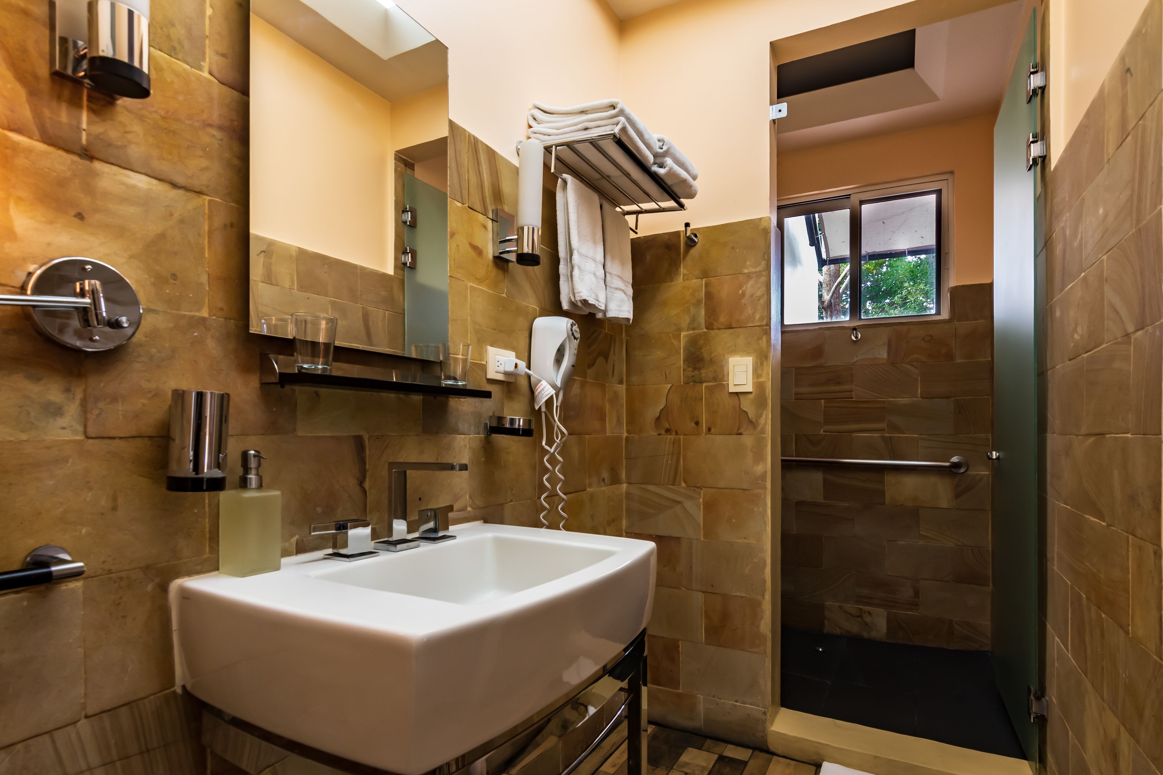 A modern bathroom with a large sink, towel rack, and a glass shower enclosure.