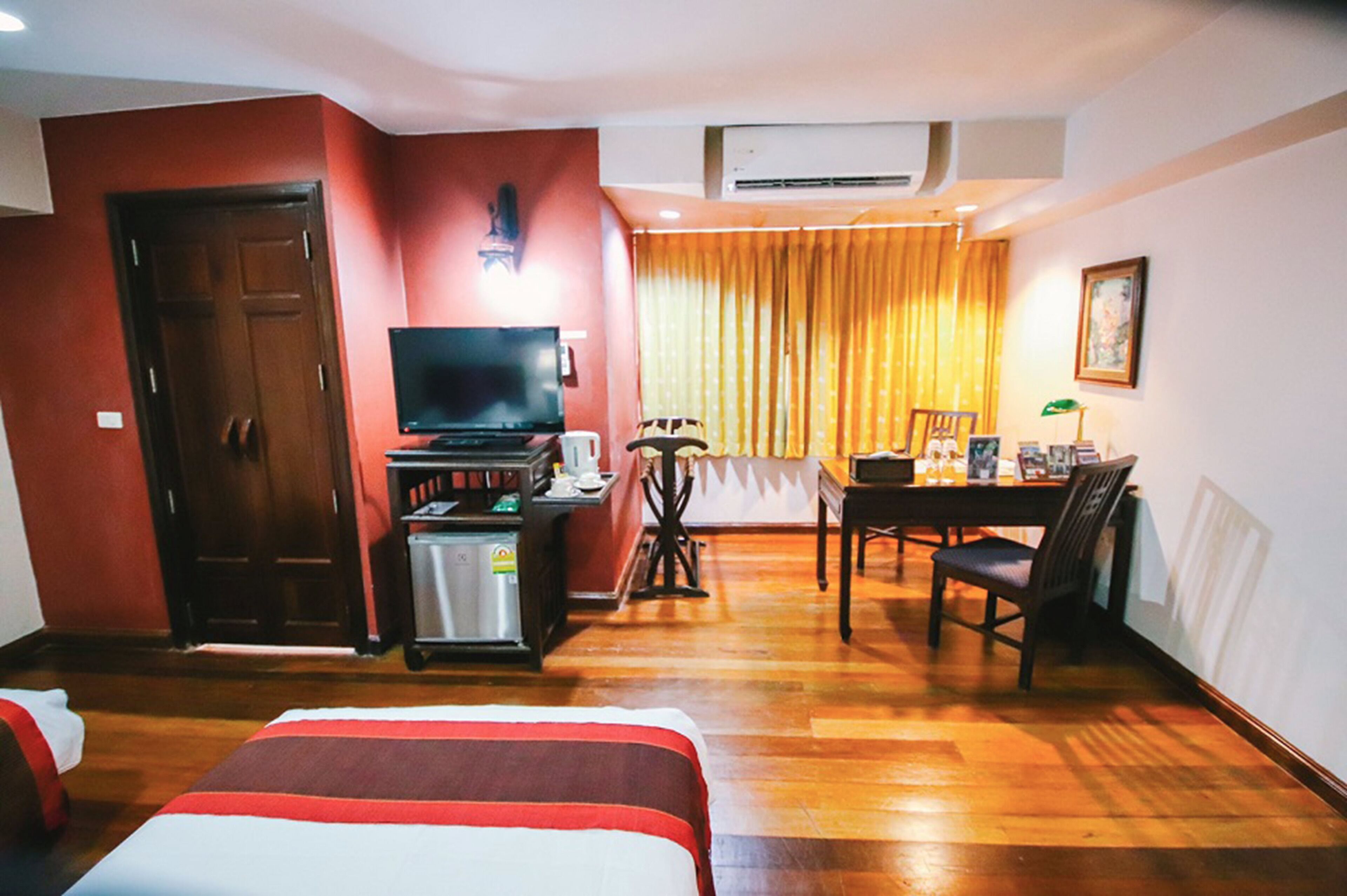 A hotel room with a bed, a desk, a television, and a dining table.
