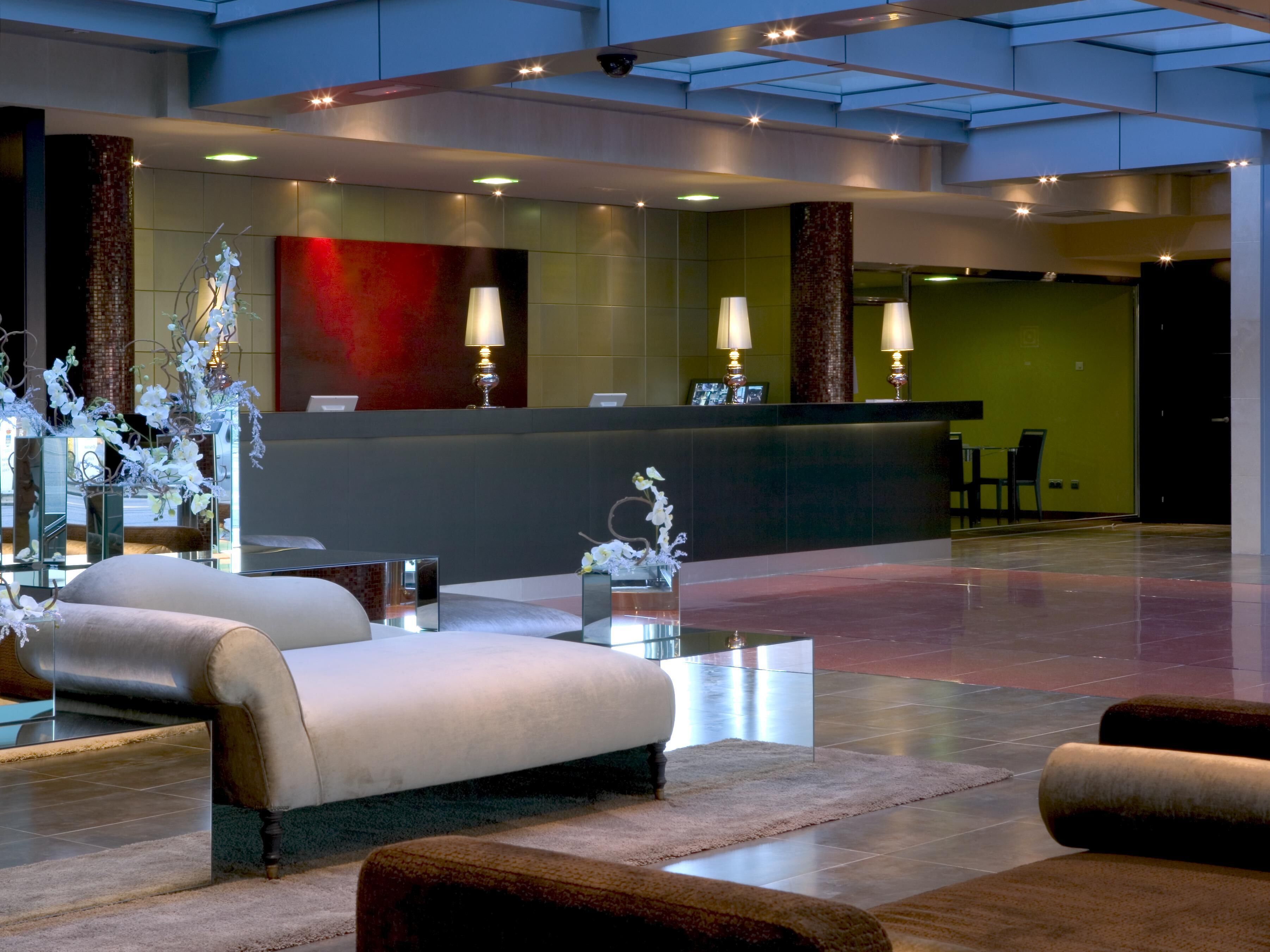 A modern lobby with a reception desk, seating area, and decorative elements.