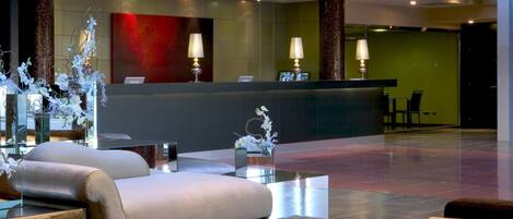 A modern lobby with a reception desk, seating area, and decorative elements.