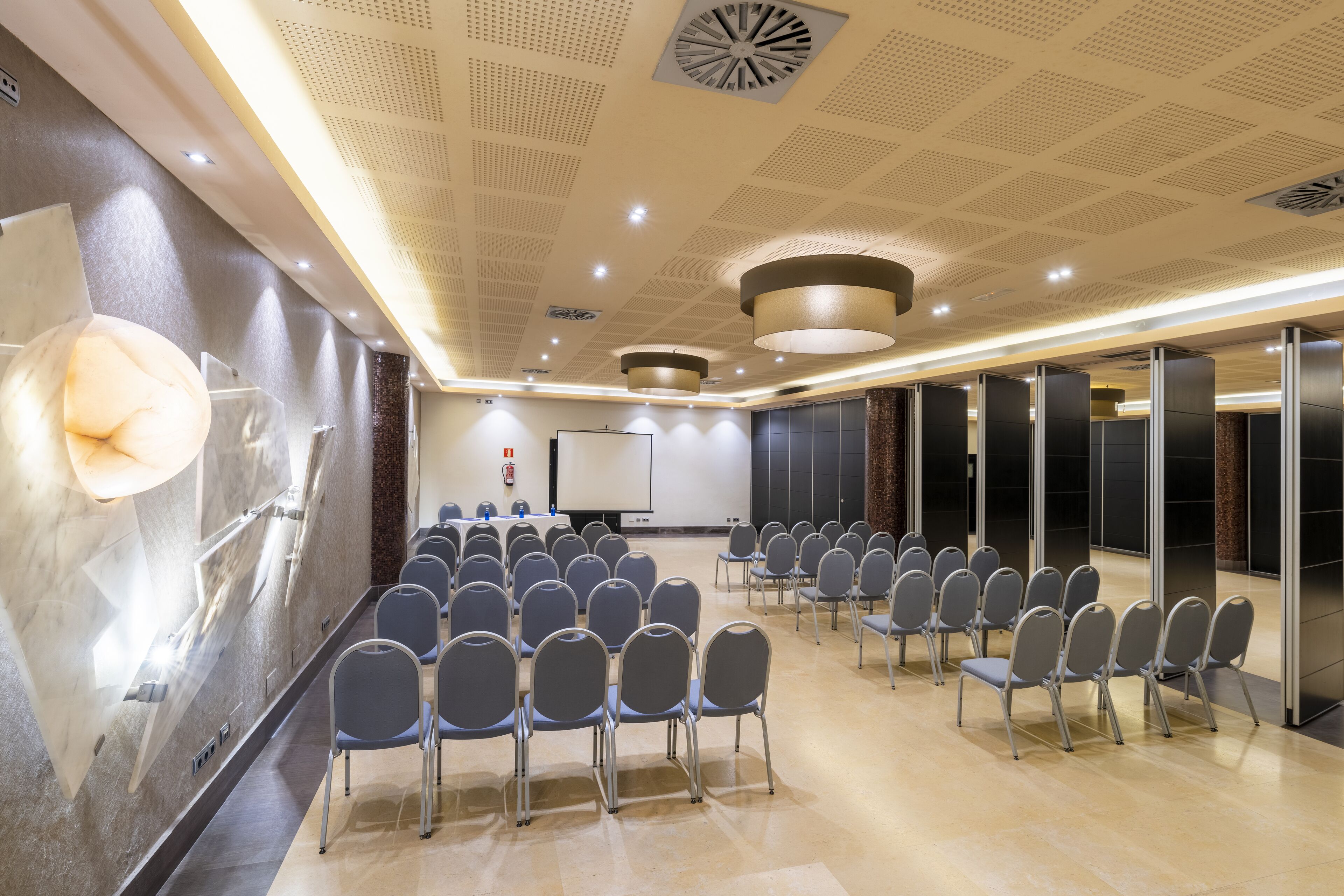 A conference room with rows of chairs, a podium, and a large screen.