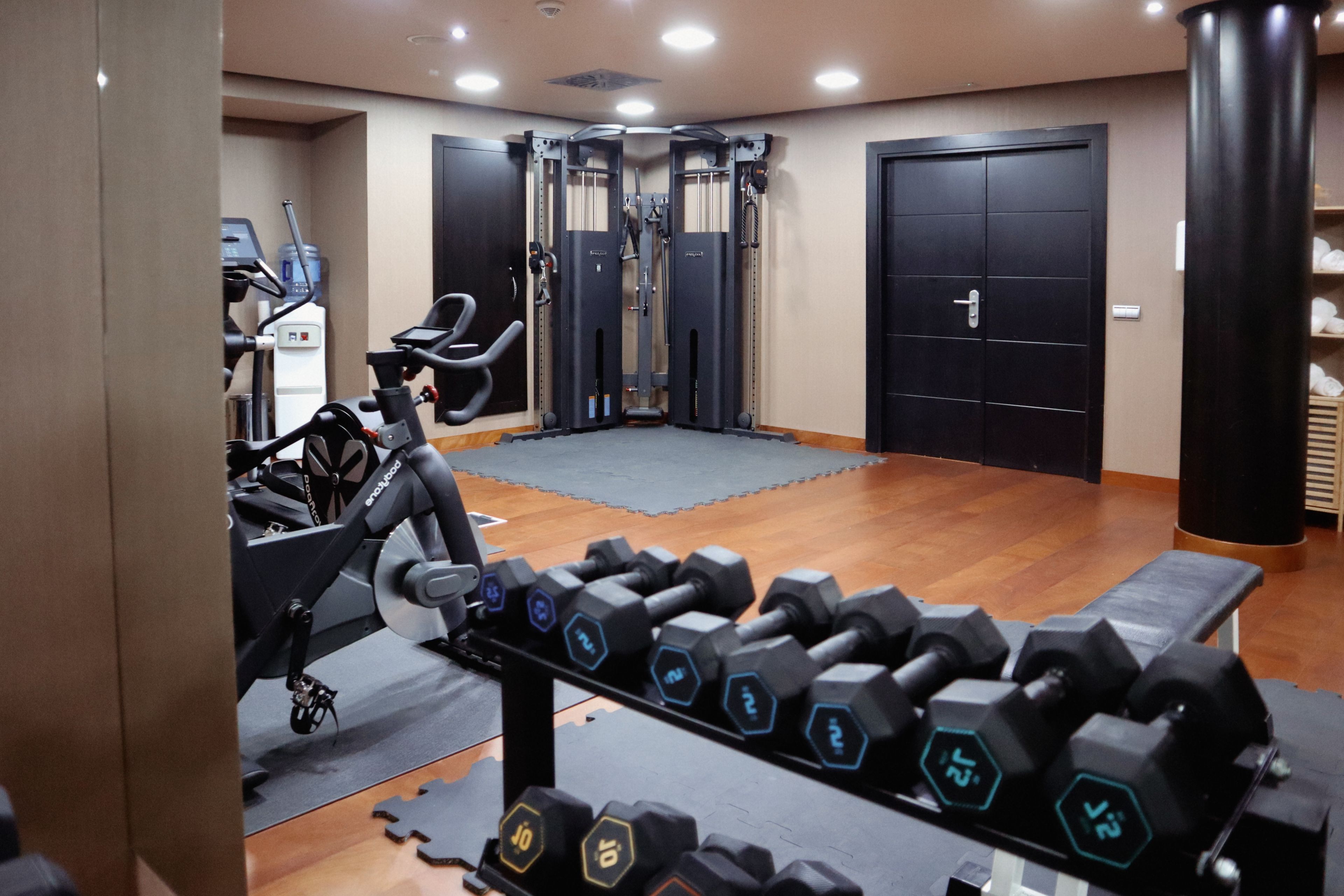 A gym with exercise equipment, a water dispenser, and a treadmill.
