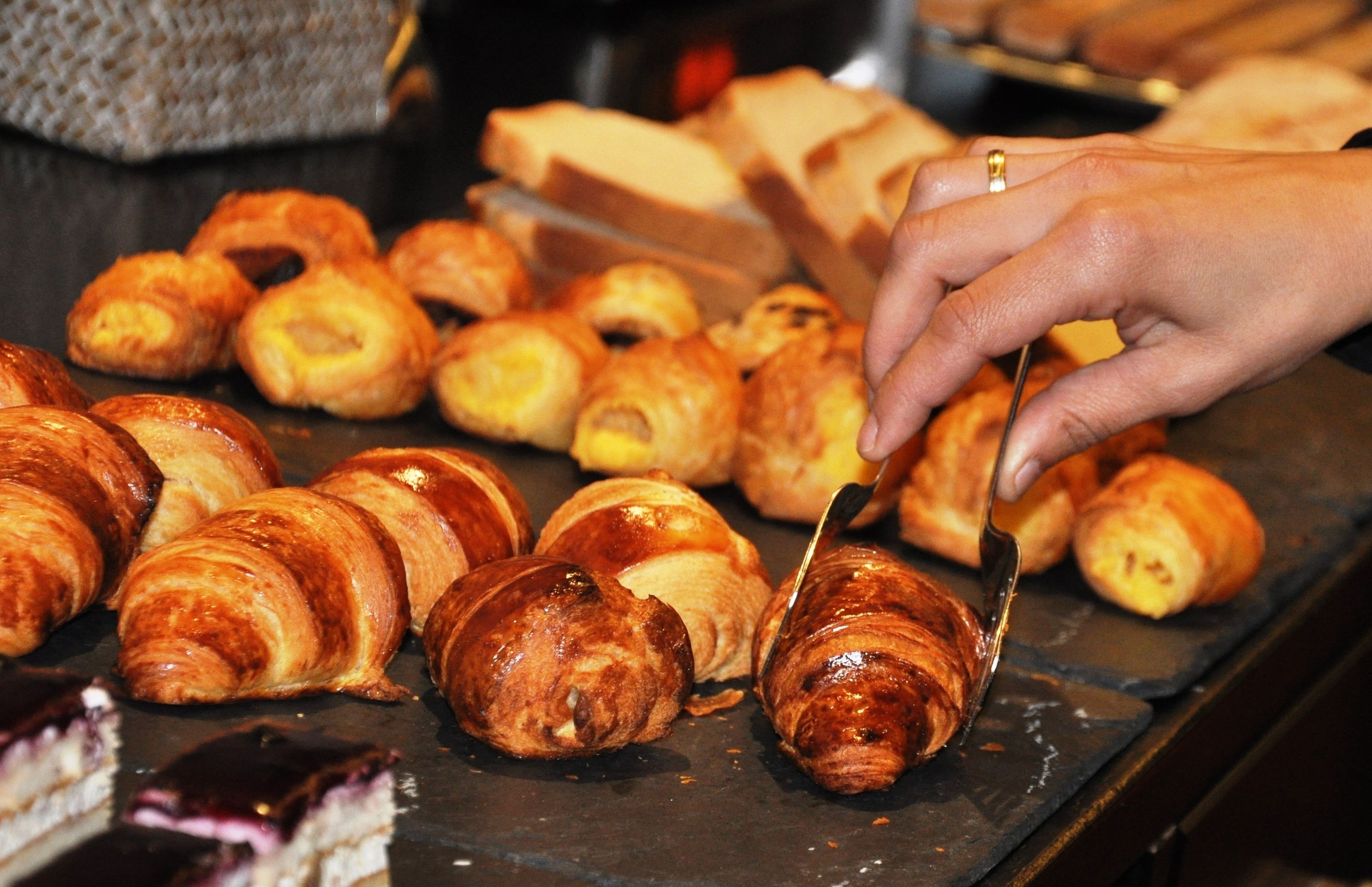 Diversos pastéis expostos, incluindo croissants e outros produtos de pastelaria.