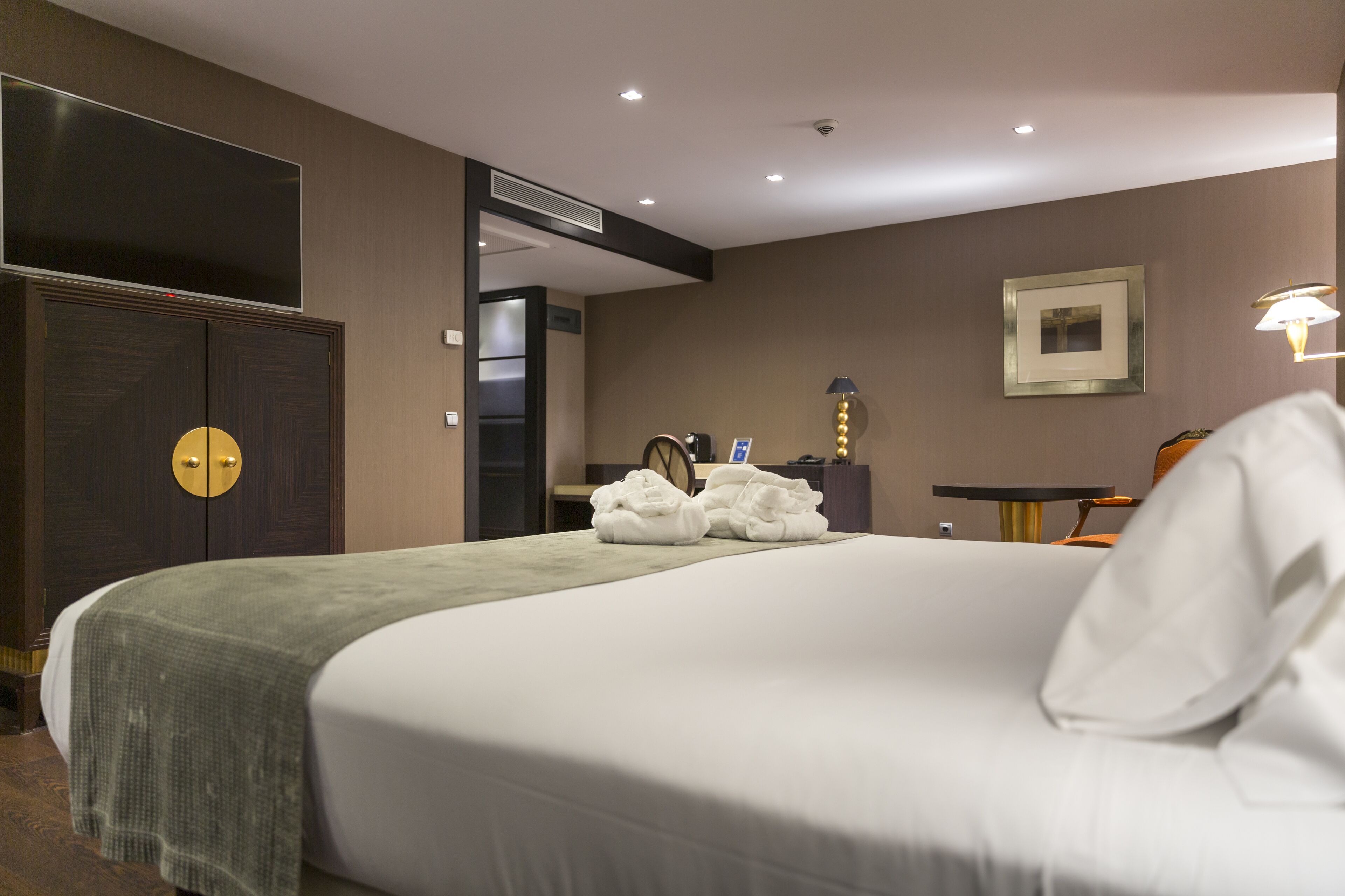 Habitació d'hotel amb un llit gran, un armari, una taula i una cadira.