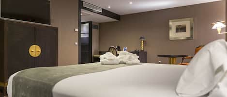 A hotel room with a large bed, a wardrobe, a desk, and a chair.