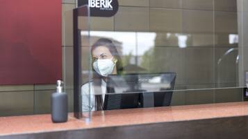 A reception desk with a sign that reads "IBERIK HOTELS" and a bottle of hand sanitizer on the counter.