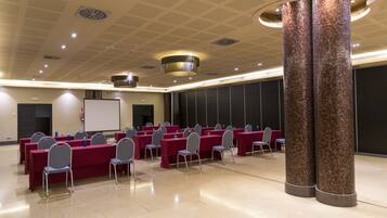 A conference room with multiple tables and chairs, a whiteboard, and a projector screen.