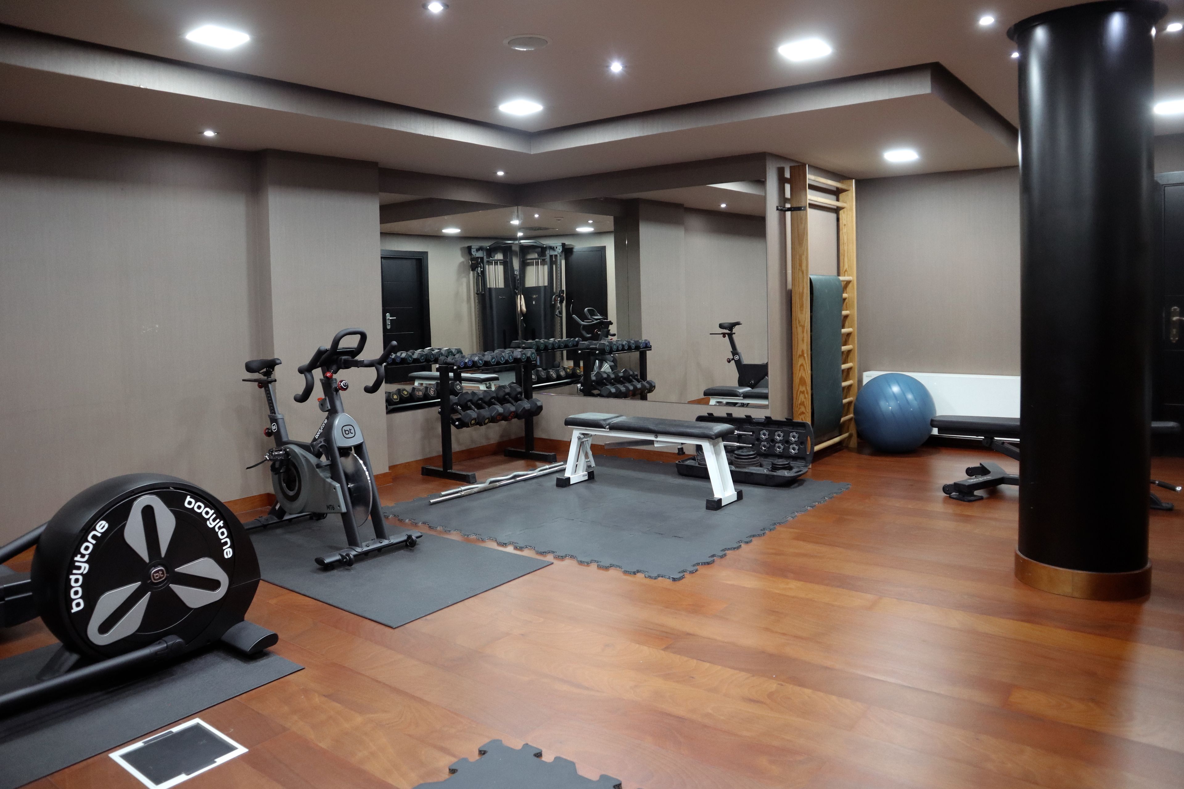 Une salle de sport équipée de matériel d’exercice, d’un banc et d’un sac de frappe.