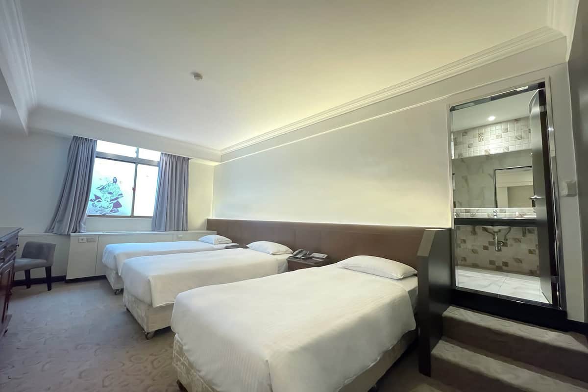 Una camera d'albergo con due letti, una scrivania, una sedia e un bagno con uno specchio.
