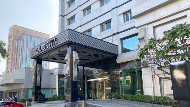 En hotellentrén med modern design, som kännetecknas av ett markant entrétak och en staty av en lejon.