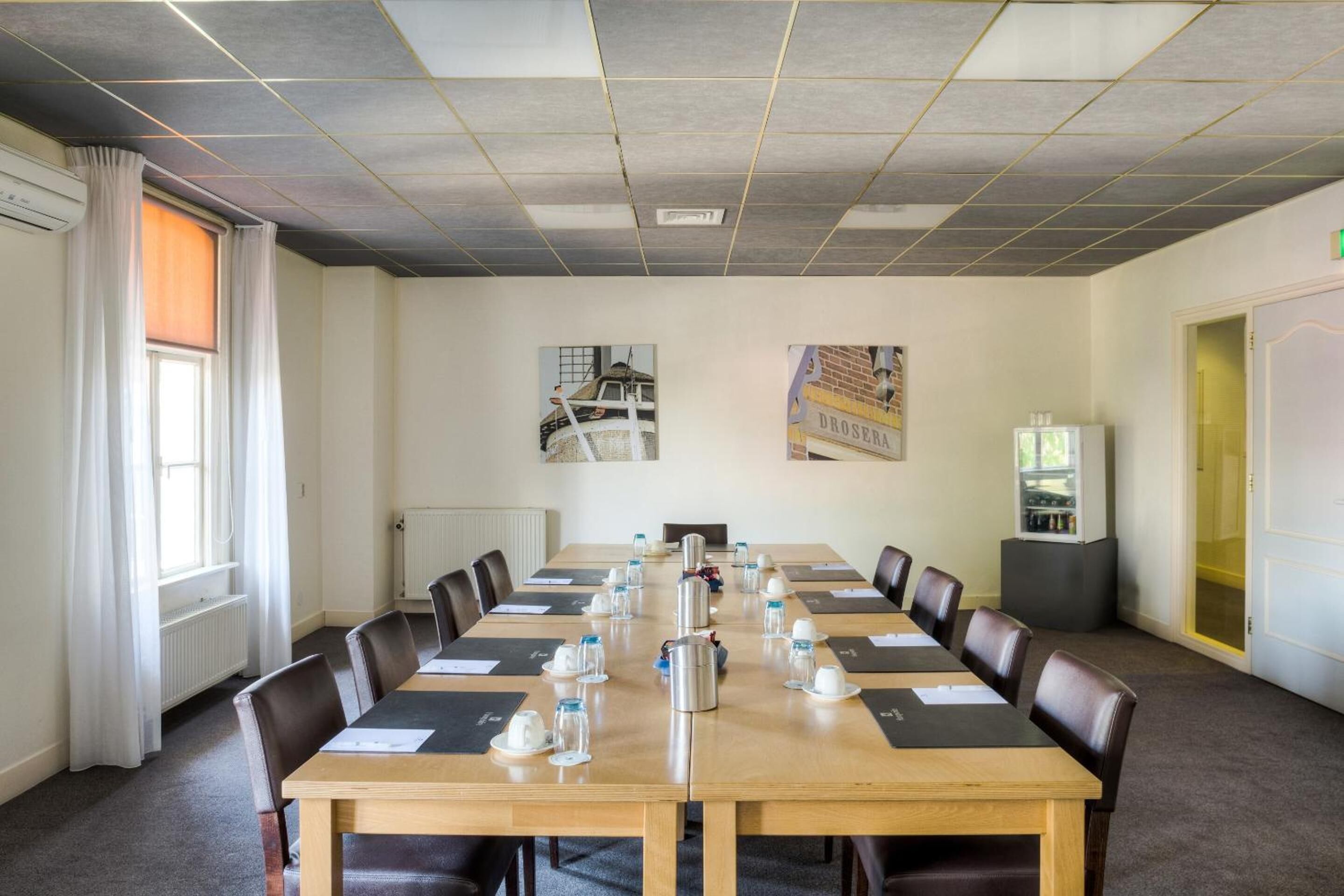 A conference room with a long table, chairs, and a projector screen.
