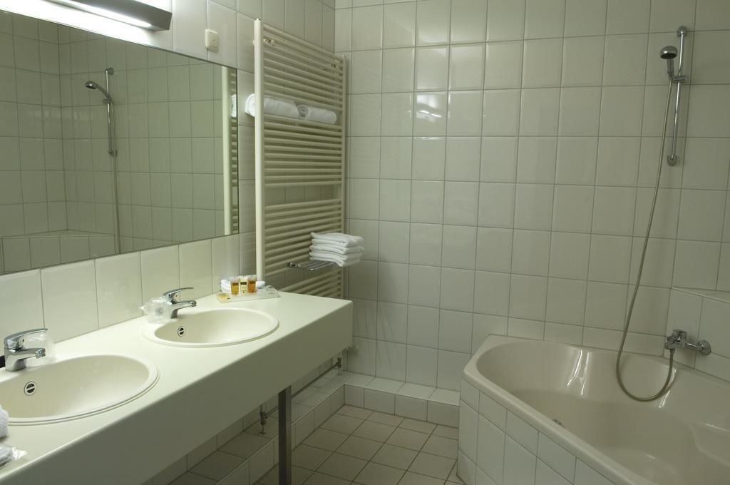 Un baño con dos lavamanos, un espejo, un toallero y una bañera.